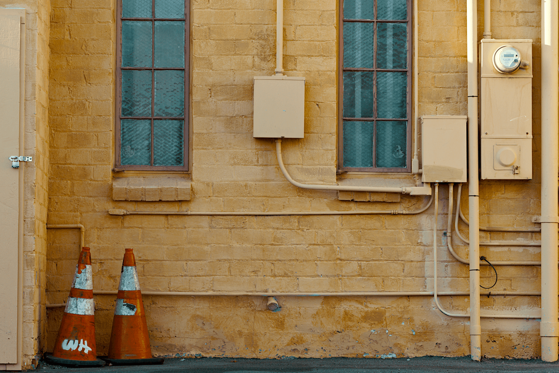 A vintage brick wall with utility pipes in a Claremont, CA alleyway.