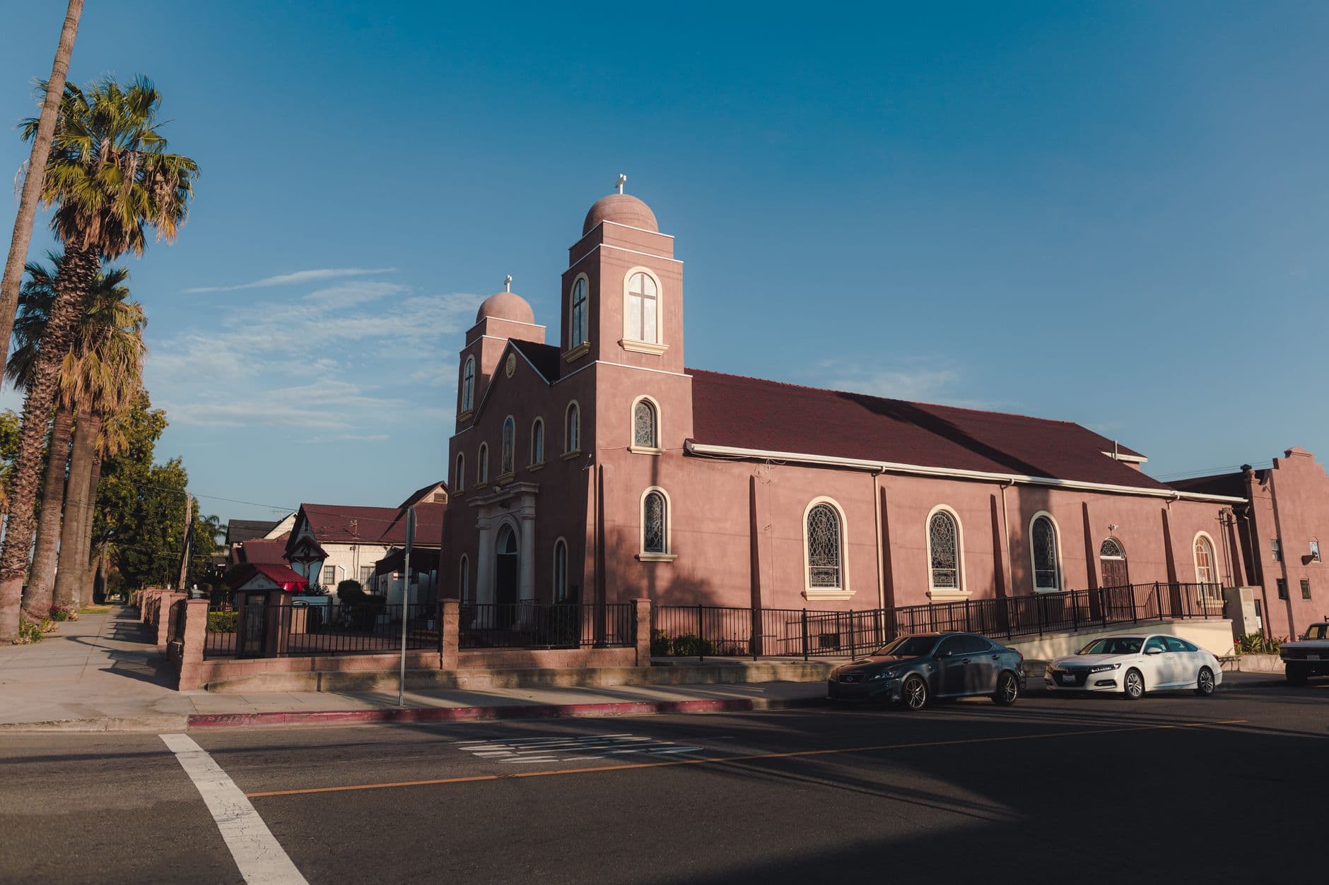 A picturesque urban church surrounded by palm trees on a bright, clear day.
