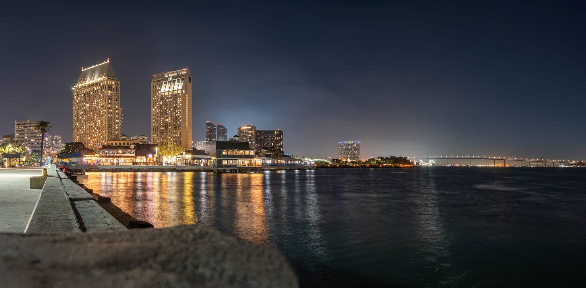 Stunning San Diego skyline featuring Coronado Bridge and glowing city lights reflecting in the bay at night.