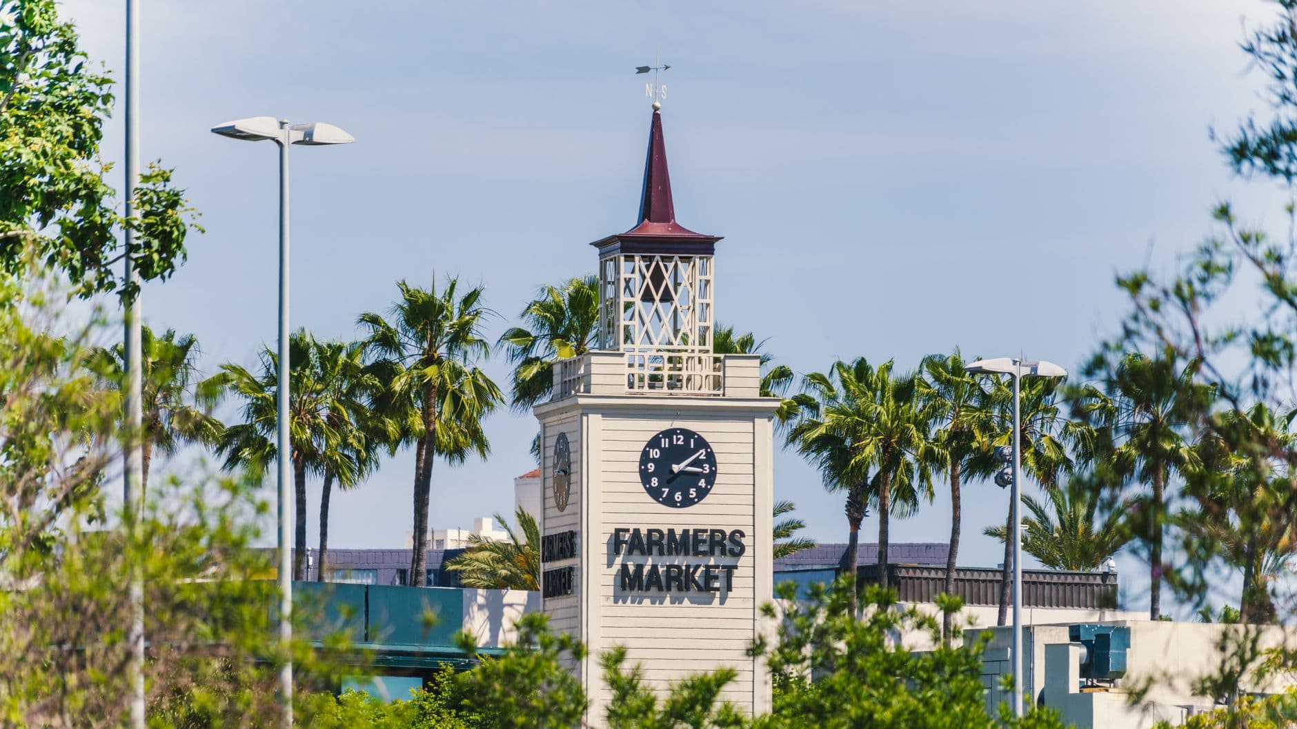 View of the historic Farmers Market clock tower surrounded by palm trees in Los Angeles.
