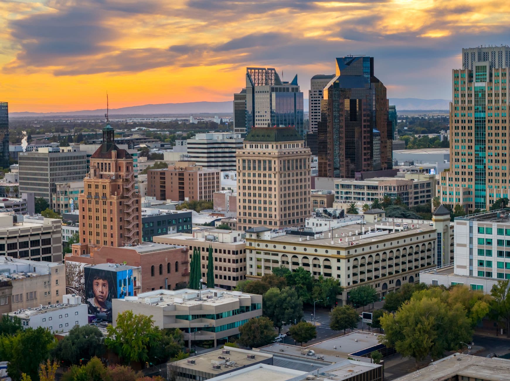 A stunning view of Sacramento's skyline at sunset, with colorful clouds and prominent buildings.