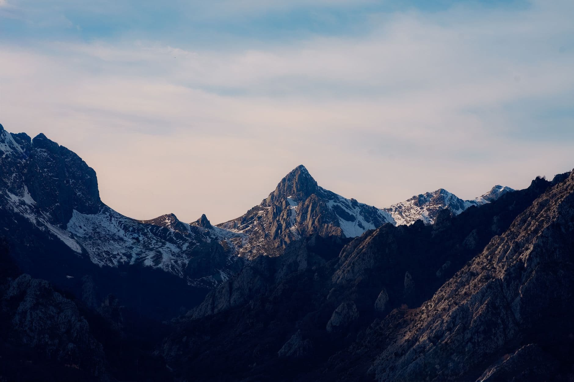 Majestic snow-capped peaks of Picos de Europa under a soft daylight sky.