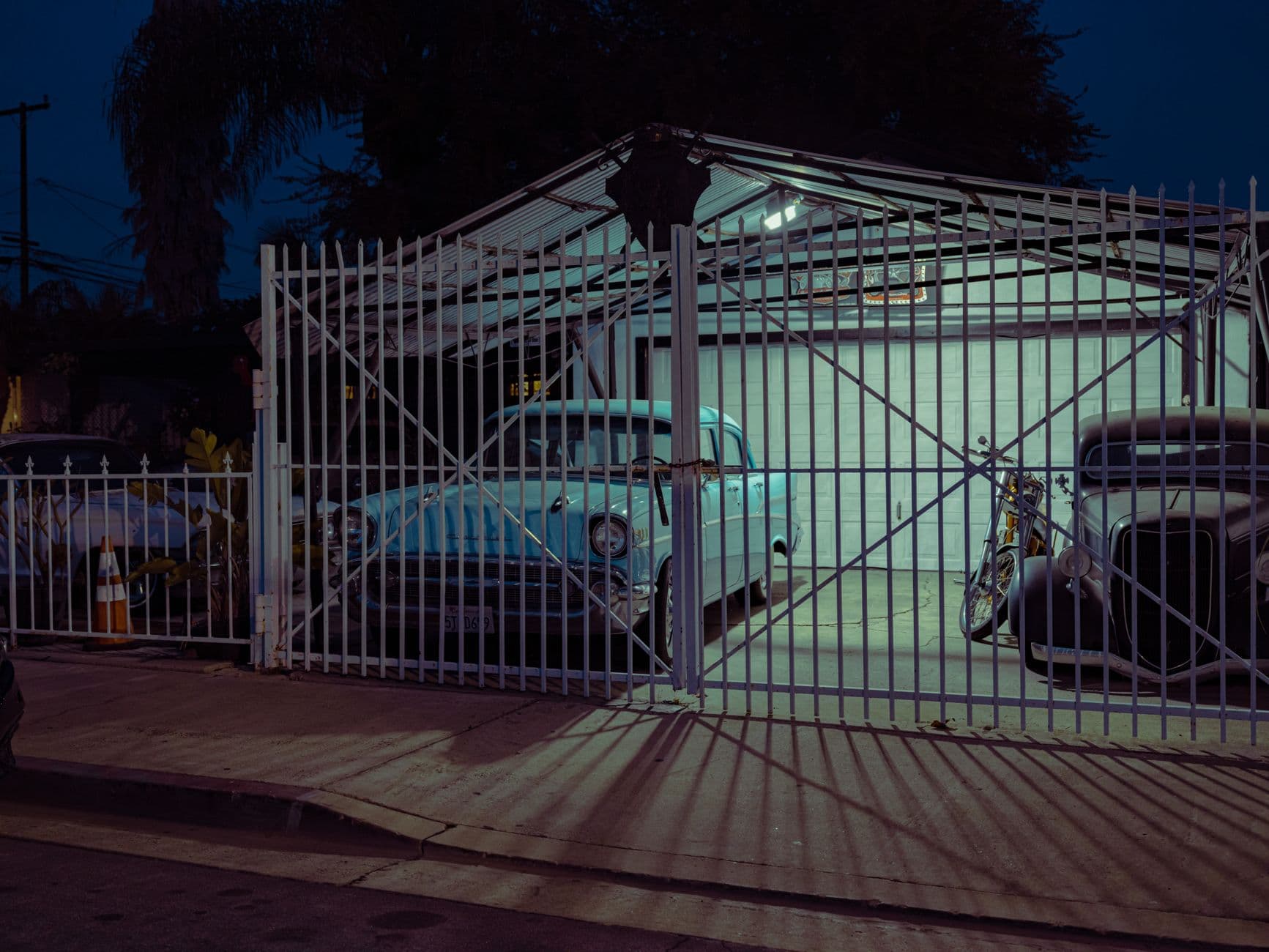A nighttime scene of vintage cars parked in an open garage in Los Angeles, CA.