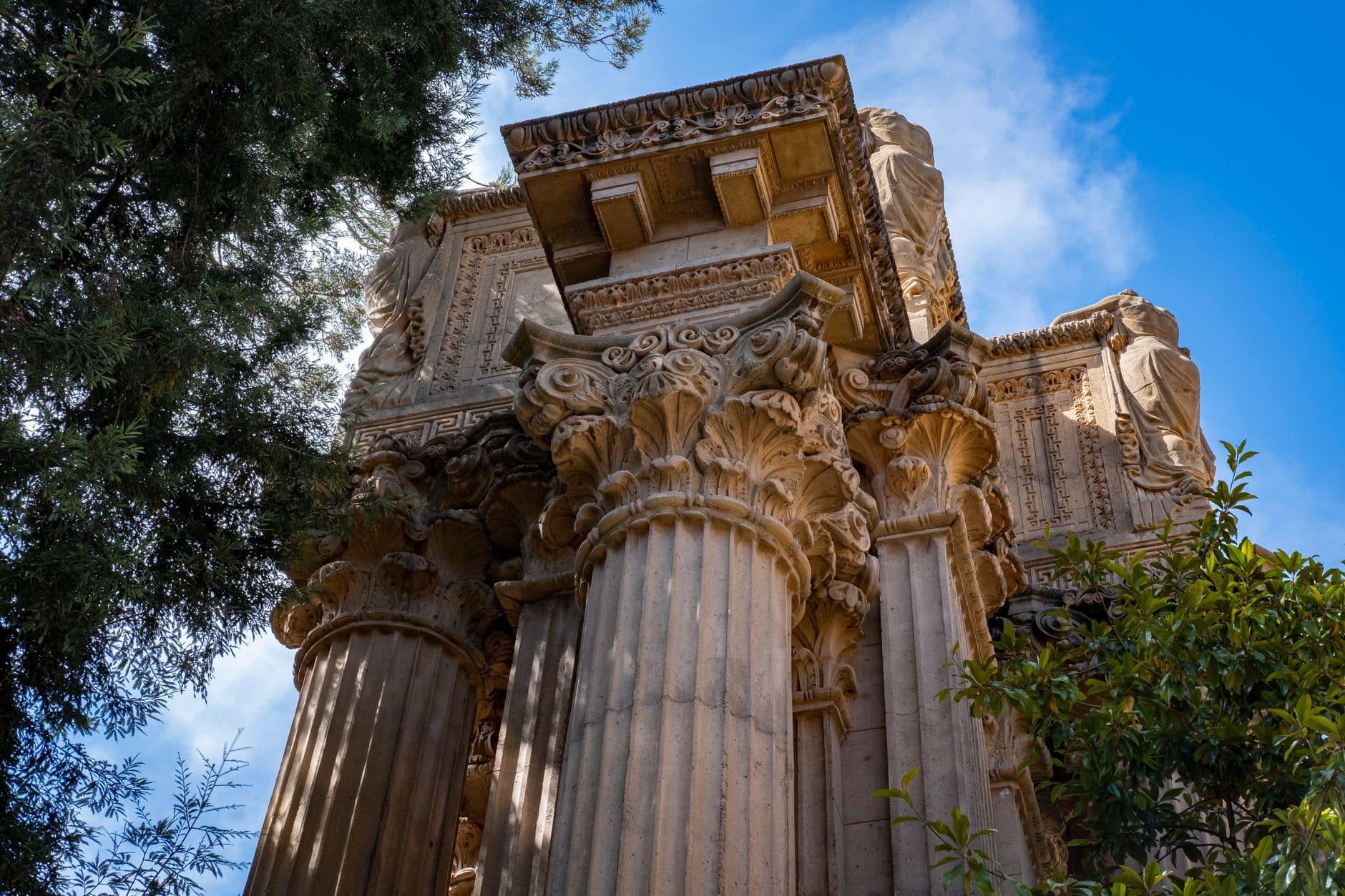 Low angle shot of ancient architectural columns with intricate carvings under a clear blue sky.